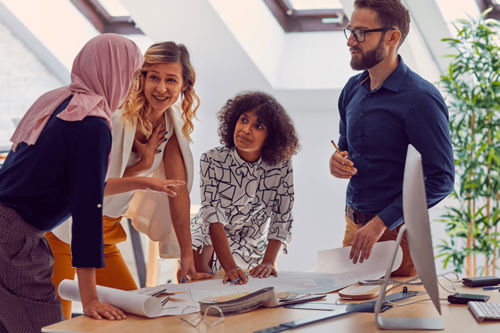 A group of people stood around a desk having a discussion